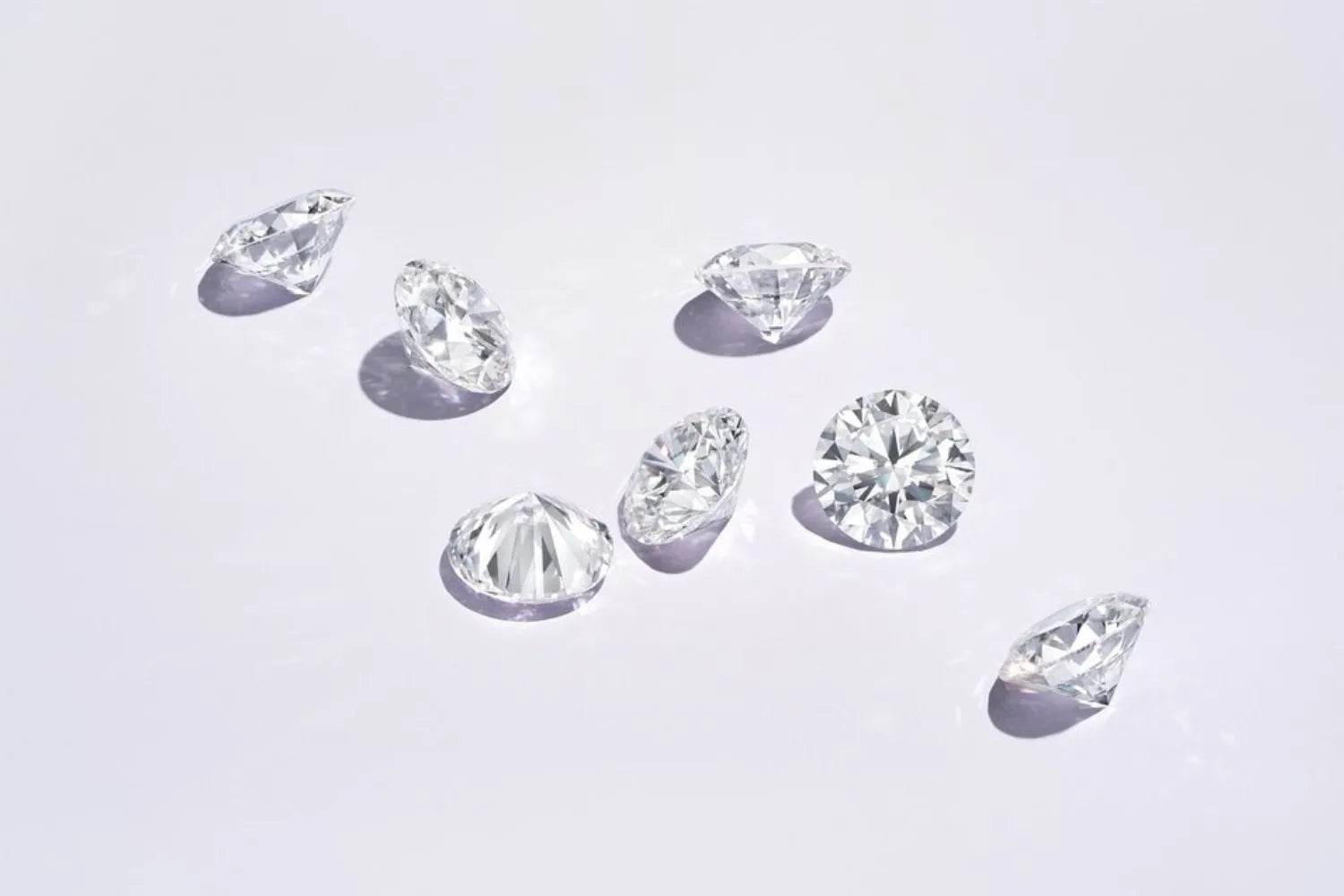 Flere ekte løse diamanter på nøytral flate – viser glans, klarhet og fasetter som kjennetegner ekte diamant.
