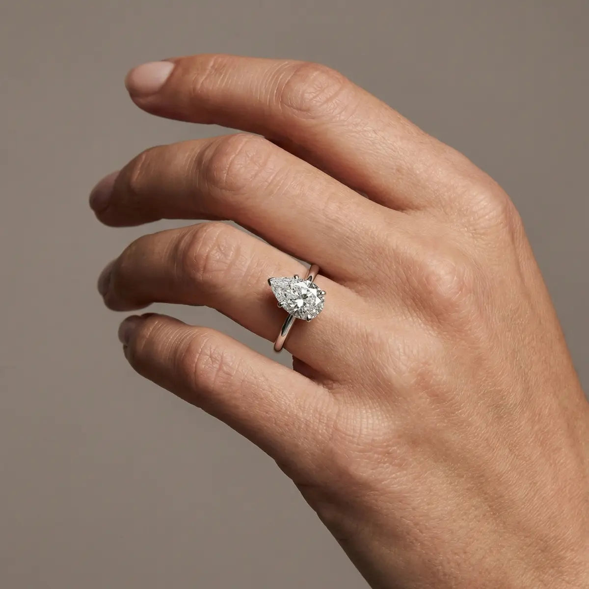 Forlovelsesring med dråpeslipt lab-diamant i hvitt gull på hånden – viser hvordan pear cut gir optisk lengde og elegant lysrefleksjon